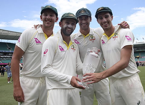 Australian bowlers Josh Hazlewood, left, Nathan Lyon, Mitchell Starc, second right, and Pat Cummins, right, hold the Ashes trophy. | AP