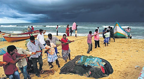 People help fishermen pull a boat out of the sea as dark clouds gather over Bay of Bengal off the Marina Beach in Chennai on Wednesday | DEBADATTA MALLICK