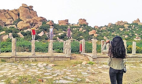Tourists stand on pillars of Salu Mantapa for a picture in Hampi