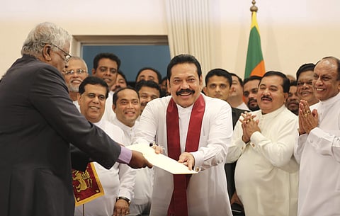 Sri Lanka's newly appointed prime minister Mahinda Rajapaksa, center, hands over inaugural documents to an official during his duties assuming ceremony in Colombo (File | AP)