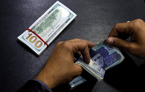 A currency trader counts Pakistani Rupee notes as he prepares an exchange of U.S dollars in Islamabad, Pakistan. (Photo | Reuters)
