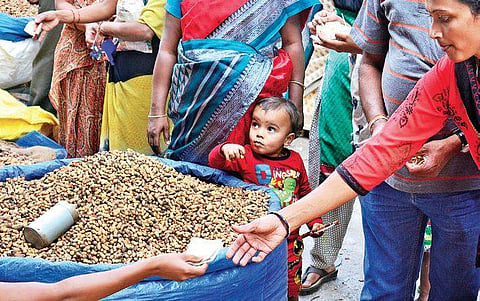 A kid plays with groundnuts as a vendor takes money from a customer at the Kadalekai Parishe on Saturday | shriram b n
