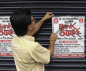 A bank employee pastes a bank strike pamphlet on the closed shutter of a bank. Image used for representational purpose only. (Photo | Reuters)