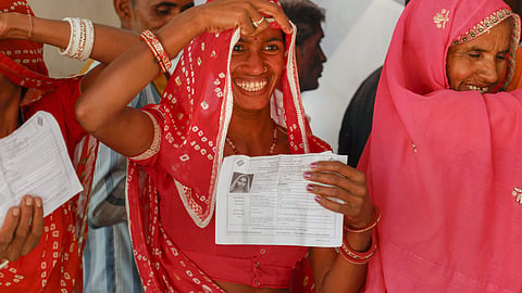 A voter smiles as she shows identity card during an election in Rajasthan. (File Photo | PTI)