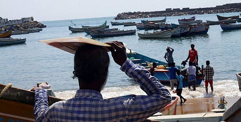 A file image of a fisherman looking at a group of young fishermen who are taking their boat into the sea at Vizhinjam. (EPS | Kaviyoor Santhosh)