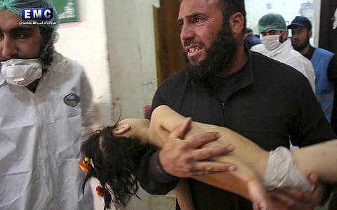 A man carrying a child following a suspected chemical attack. (Photo | AP)