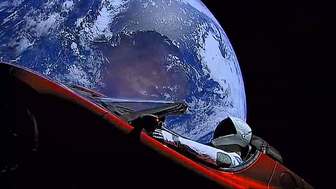 Elon Musk's tweet was attached with an image of a floating cherry-red Tesla sports car with a space-suited mannequin strapped in the driver’s seat and the Earth hanging behind it. (Twitter | Elon Musk)
