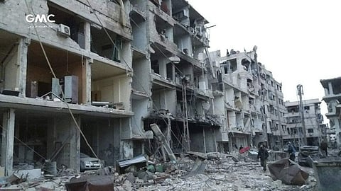 Syrians walk between destroyed buildings during airstrikes and shelling by Syrian government forces in Ghouta. (photo | AP)