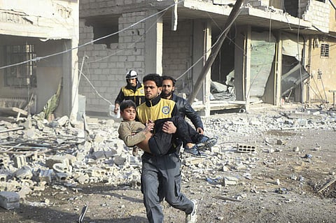A member of the White Helmets carrying a boy who was wounded during airstrikes and shelling by Syrian government forces in Ghouta. (Photo | AP)