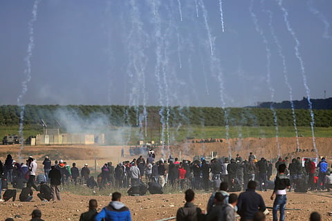 Teargas canisters fired by Israeli troops fall down on Palestinians during a demonstration near the Gaza Strip border with Israel, in eastern Gaza City. | AP