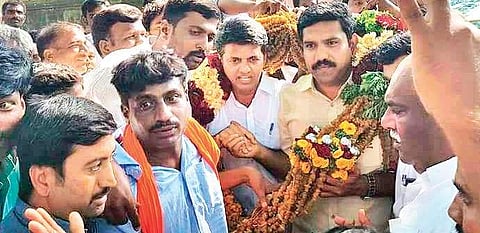 BJP workers garland B Y Vijayendra and party candidate Preetham Nagappa in Hanur on Saturday