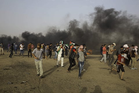 Palestinian protesters run for cover from teargas fired by Israeli troop near the fence of the Gaza Strip's border with Israel, during a protest on the second Friday of the holy month of Ramadan, east of Khan Younis, in the Gaza Strip, Friday, May 25, 201