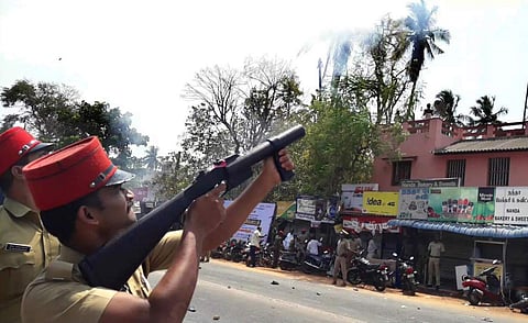 A policeman firing tear gas following a group clash during public hearing at Kalapet, Puducherry on Tuesday. | (G Pattabiraman | EPS)