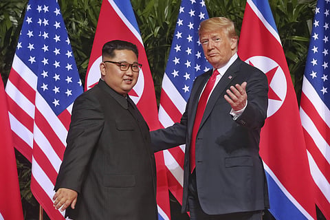 U. S. President Donald Trump gestures toward the media with North Korea leader Kim Jong Un at the Capella resort on Sentosa Island on June 12, 2018 in Singapore. | AP