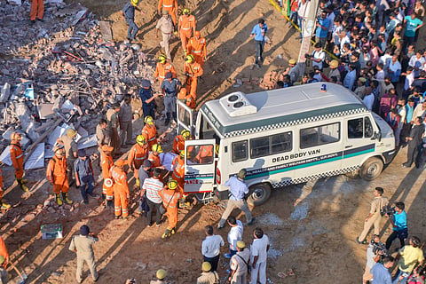 Rescue workers carry the body of a victim at the site of a collapsed building at Shahberi village in Greater Noida West on Wednesday July 18 2018. | PTI