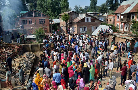 Villagers look on at the debris of a damaged houses where three Lashkar-e-Taiba and Hizbul Mujahideen militants were killed during an encounter with security forces at Redwani area of Kulgam district in south Kashmir on Sunday July 22 2018. | PTI