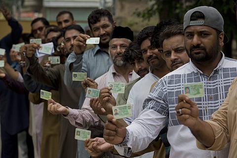 Pakistani voters display their ID cards while waiting in the queue to cast their votes. (Photo | PTI)