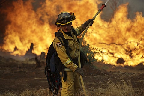 A firefighter makes a stand in front of an advancing wildfire as it approaches a residence Saturday, July 28, 2018, in Redding ,California. ( Photo | AP)