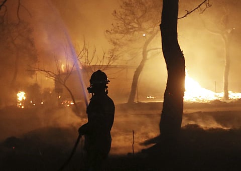 A firefighter sprays water on the fire in the town of Mati, east of Athens, Monday, July 23, 2018. (Photo | AP)