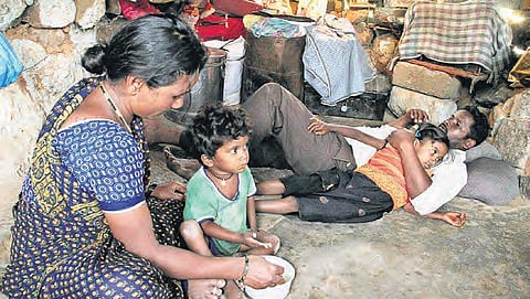 A woman feeds her child sitting in a cramped room at Keshav Nagar, in Hyderabad on Monday. | s senbagapandiyan