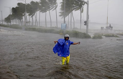 A traffic enforcer gestures at motorists to avoid a flooded street at the onslaught of Typhoon Mangkhut which barreled into northeastern Philippines before dawn Saturday, Sept. 15, 2018 in Manila, Philippines. (Photo | AP)