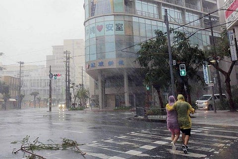 A couple crosses the street in heavy rain in the city centre of Naha, Okinawa prefecture, on Sept 29, 2018. (Photo | AFP)