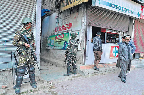 Troopers stand guard outside a chemist in Srinagar. Security has been enhanced a day after two men were killed in Kashmir | ( Photo | PTI )