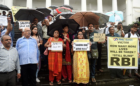 Depositors of the PMC bank display placards during a protest over the RBI 's curb at RBI headquarters in Mumbai. (Photo | PTI)