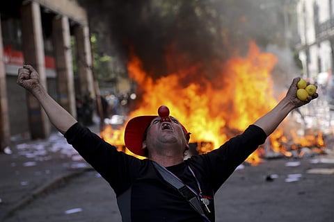 An anti-government demonstrator screams in font of a burning barricade in Santiago, Chile, Tuesday, Oct. 22, 2019. Protests in the country have spilled over into a fifth day, even after President Sebastian Pinera cancelled the subway fare hike that prompt