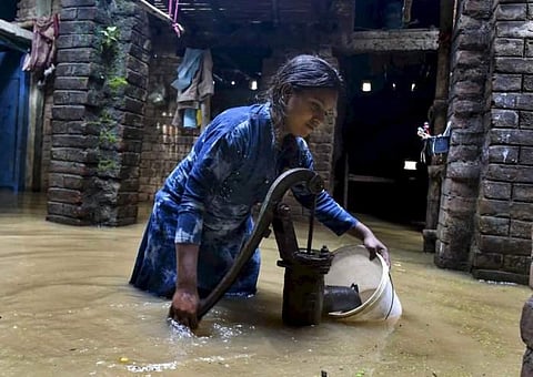 A woman collects portable water from a handpump in flooded area of Beldari Chak, Patna (Photo | PTI)