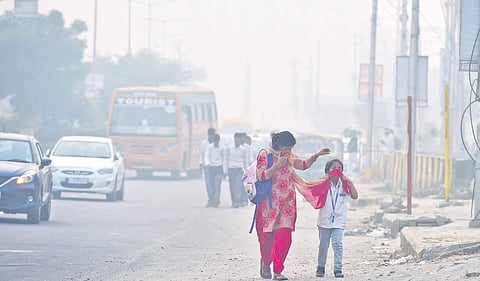 A woman and her daughter cover their faces to protect themselves from the toxic air in New Delhi (Photo | PTI )
