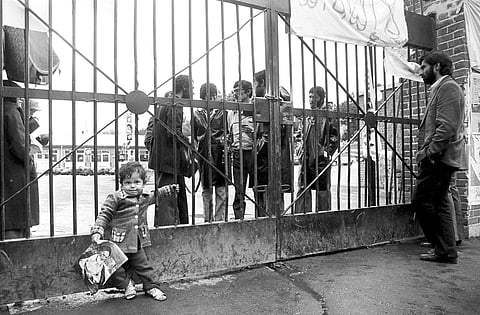 An Iranian child holds a photo showing Ayatollah Ruhollah Khomeini in front of the entrance of the U.S. Embassy on the third day of the occupation of the building by Iranian students. (Photo | AP)