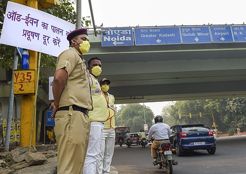 Civil Defence volunteers wearing masks stand near a placard asking people to obey the odd-even rule at ITO in New Delhi Monday Nov. 4 2019. | (Photo | PTI)