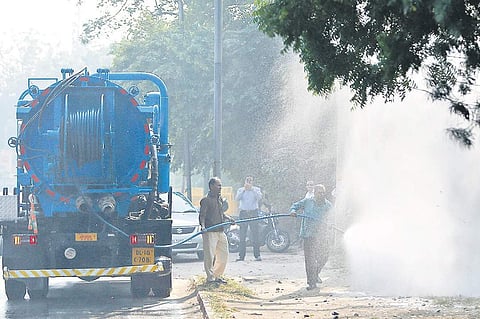 An SDMC worker sprays water on trees on Tuesday as part of measures to reduce the amount of dust in the air. (Photo | EPS/Arun Kumar)
