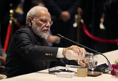India's Prime Minister Narendra Modi pours water into a glass as he waits for transmission glitch to his voice receiver to be fixed during The Association of Southeast Asian Nations ASEAN-India summit in Nonthaburi, Thailand, Sunday, Nov. 3, 2019. | (Pho
