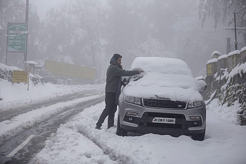 A resident clears snow from his car windshield after fresh snowfall in Patnitop (Photo| PTI)