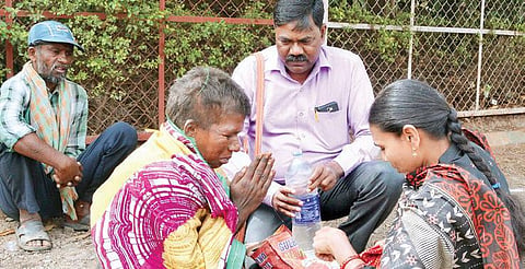 Kariyappa Shirahatti and his wife Sunanda offering clothes and food to a woman at Hubballi railway station | D Hemanth