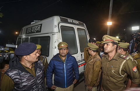 Policemen stand near an ambulance carrying the mortal remains of the rape victim who succumbed to severe burns in Delhi hospital arrived at her native village in Unnao district Saturday Dec.7 2019. (Photo | PTI)
