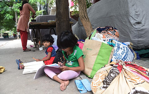 Sitting next to a pile of clothes, a six-year-old girl, who is an LKG student, is busy finishing her homework (File Photo | Vinod Kumar T/EPS)