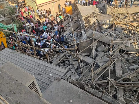 People gather near the debris after the collapse of the under-construction building. (Photo | EPS)
