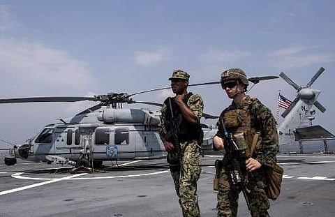US Navy personnel walk past a Sikorsky MH-60 Seahawk helicopter after the USS Blue Ridge docked during a visit in Manila Bay on March 13, 2019. | AFP