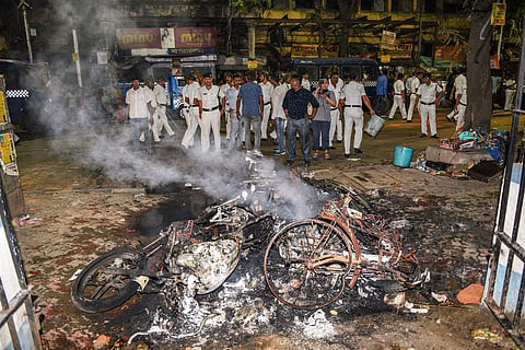 Police personnel douse burning vehicles caused by a mob during BJP President Amit Shah's election roadshow in Kolkata (Photo | PTI)