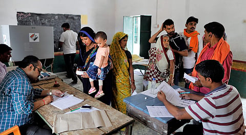 Election officers check the identity of voters before allowing them to cast their votes during the seventh and final phase of national elections, on the outskirts of Varanasi. (Photo | AP)