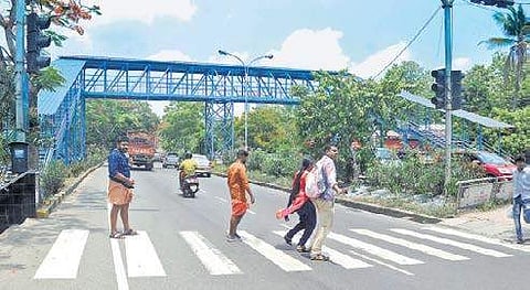 Pedestrians crossing the road despite the presence of a foot over bridge A Sanesh