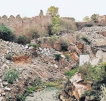 Natural rock formations disrupted near a fort's wall.