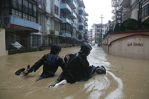 A Nepalese pulls his motorbike and wades past a flooded street in Kathmandu | AP