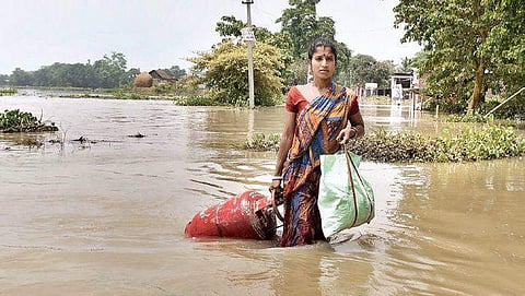A woman carries her belongings from a flood affected area to a safer place, following heavy monsoon rain in Morigaon district of Assam on Friday | Pti
