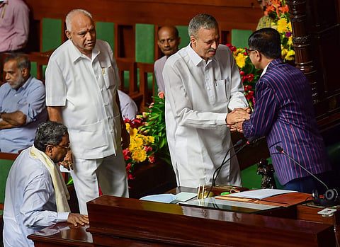 Newly elected Karnataka Assembly speaker Vishweshwar Hegde Kageri greets deputy speaker Krishna Reddy as he is escorted by Karnataka Chief Minister B S Yediyurappa and Congress leader Siddaramaiah to the speaker chair during the assembly session to announ