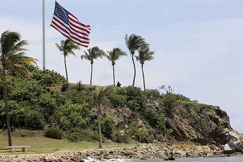 A man stands near a U.S. flag at half staff on Little St. James Island, in the U. S. Virgin Islands, a property owned by Jeffrey Epstein. | ( Photo |AP )