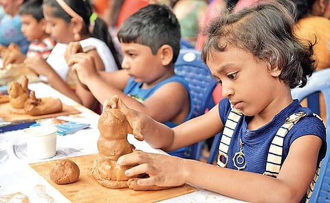 Children try their hand at moulding a Ganesha idol at National College Grounds in Basavanagudi, on Sunday. People from various walks of life and all age groups participated in the event to create a new record of the most number of people sculpting with m